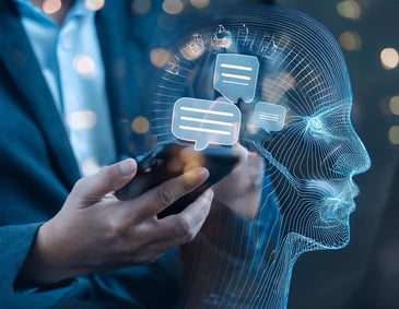 Mãos de um homem segurando um smartphone com uma projeção holográfica de perfil humano e balões de fala, simbolizando a Inteligência Artificial na Comunicação Interna.